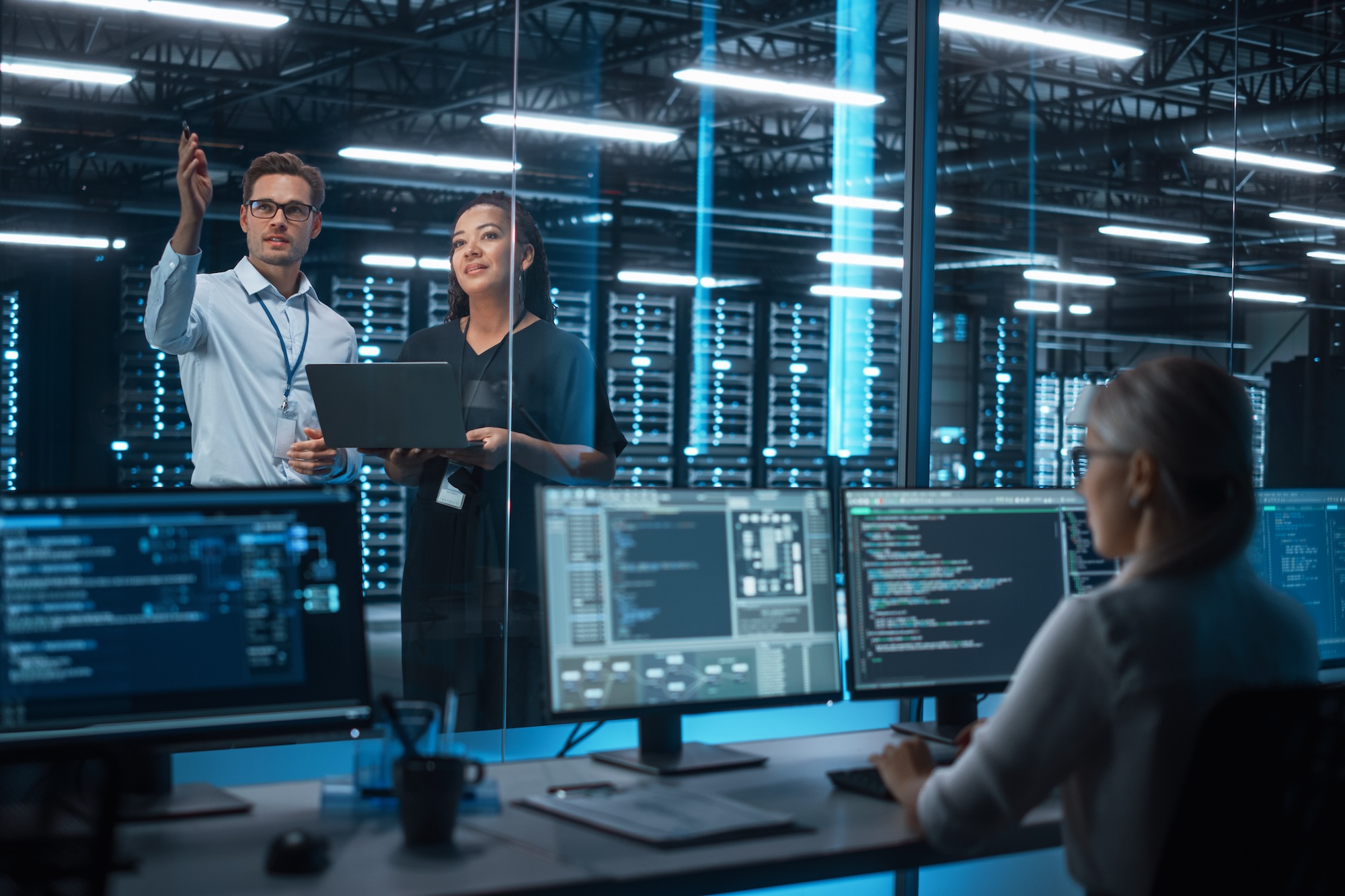 Female e-Business Entrepreneur and Male IT Specialist Discussing Something and Use Laptop in Big Data Center Server Room. Work on Web Services Cloud Computing SAAS Concept