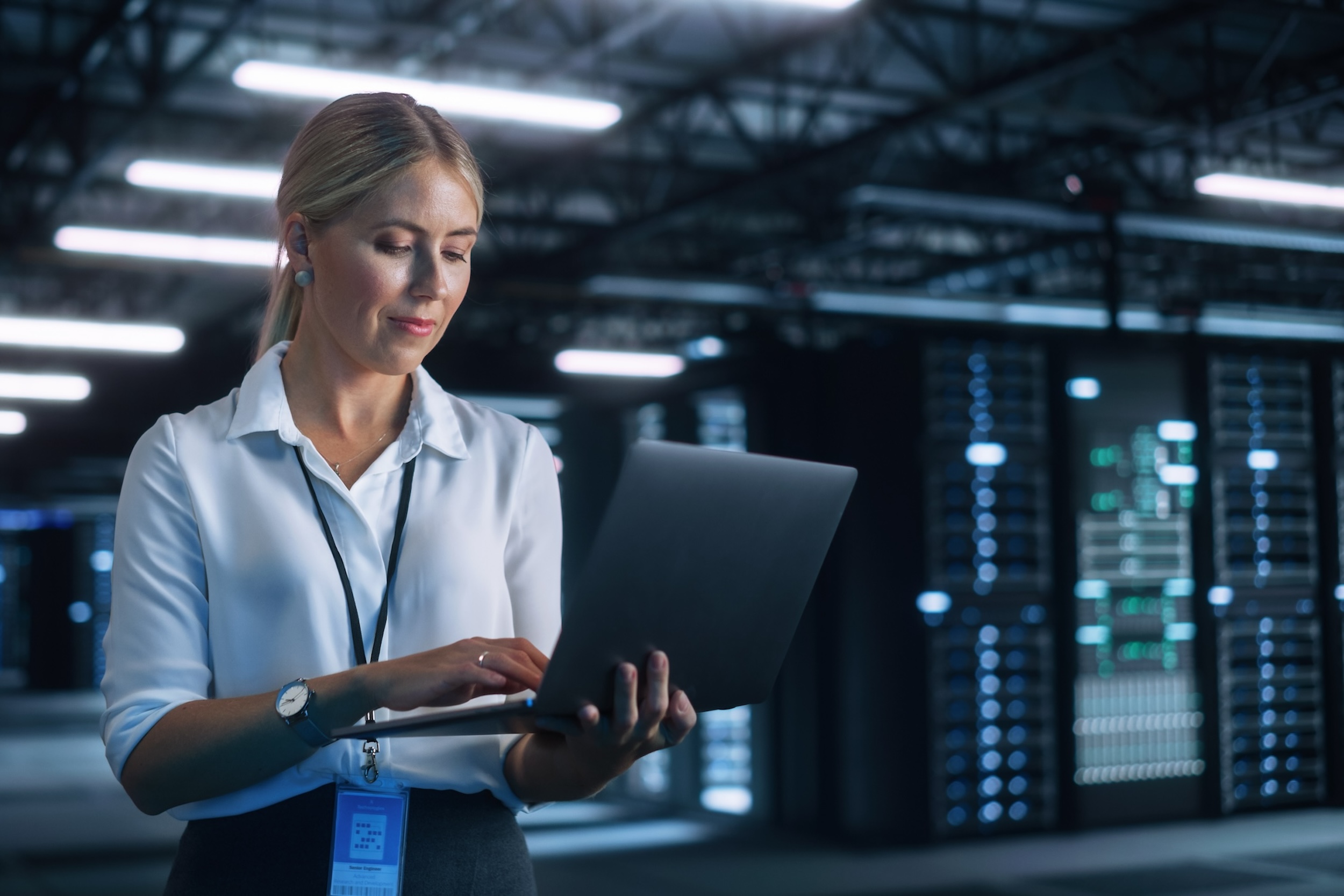 Portrait of Successful Female Chief Engineer or CEO Using Laptop Computer to Optimise Server Farm Cloud Computing Facility at the Evening Office. Cyber Security, Network Protection Concept