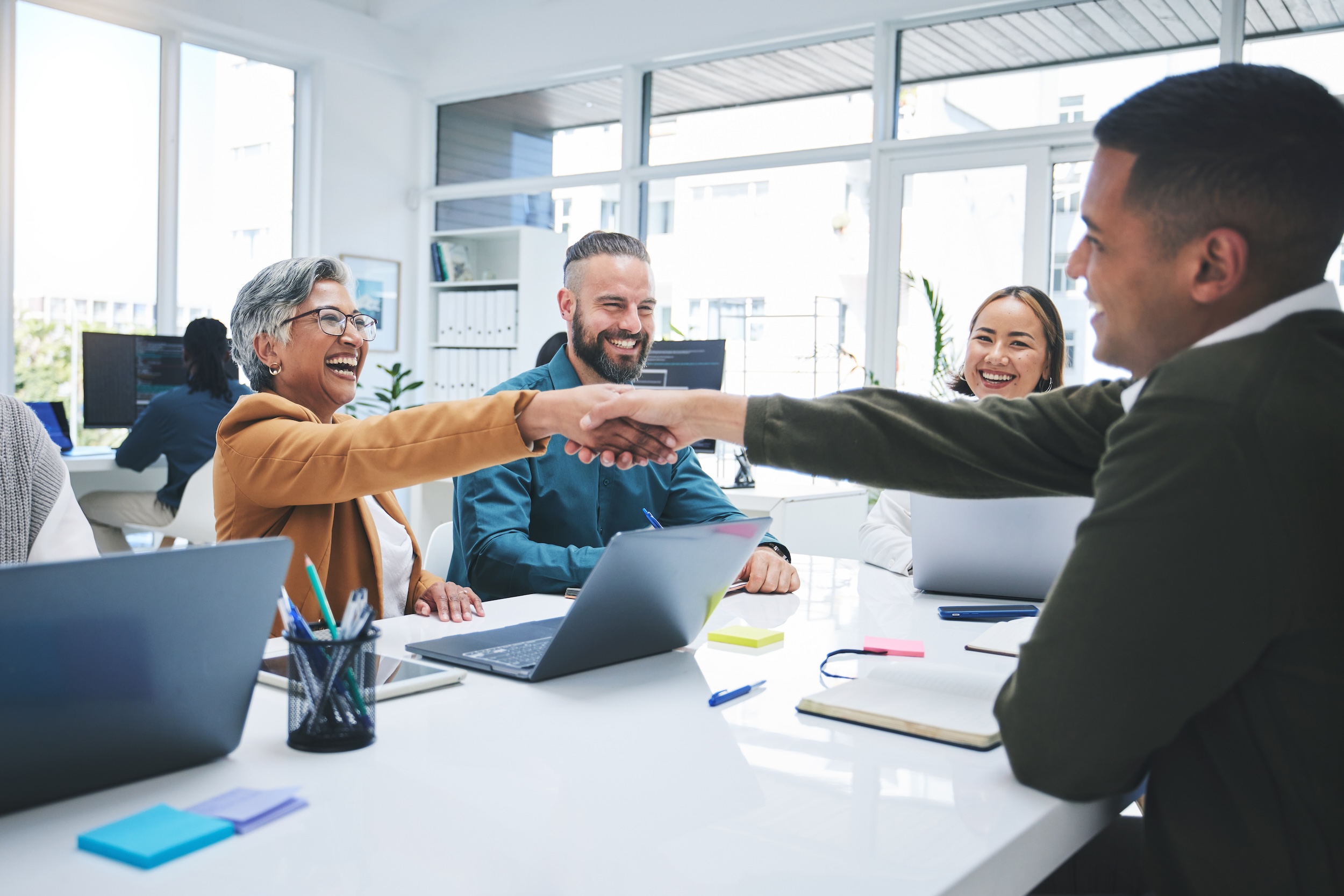 Creative people, handshake and meeting in hiring, partnership or deal agreement together at the office. Group of employees shaking hands in recruiting, company growth or startup at the workplace.